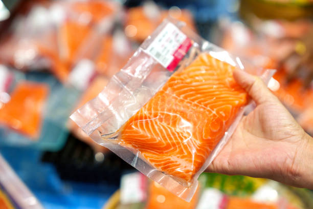 Close up of a shopper holding a vacuum packed fresh salmon fillet at a local market